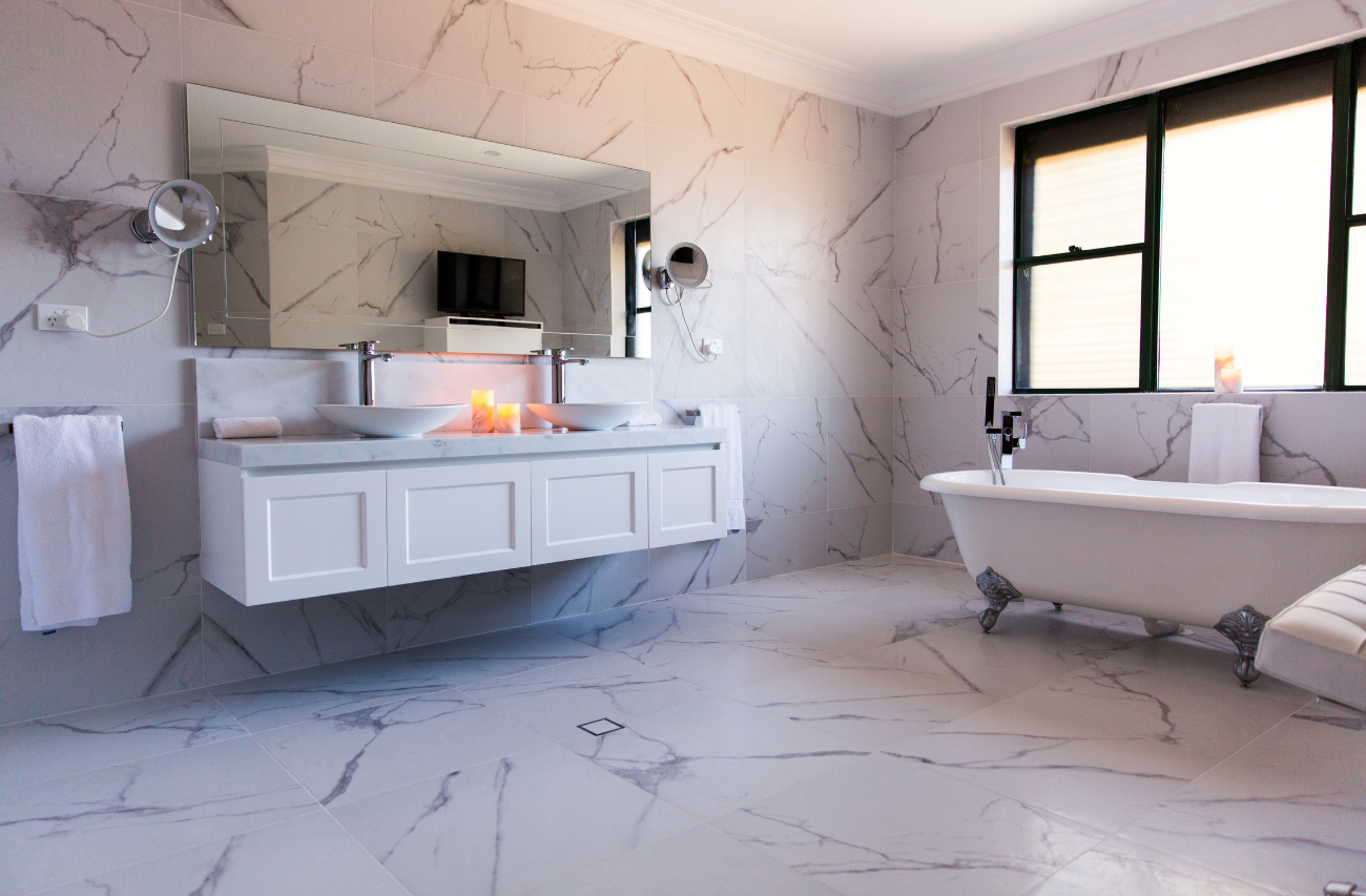 3/4 angle shot of a luxury residential marble bathroom in Chatswood, Sydney by Renovahouse with marble tiled walls and floors and freestanding bathtub.